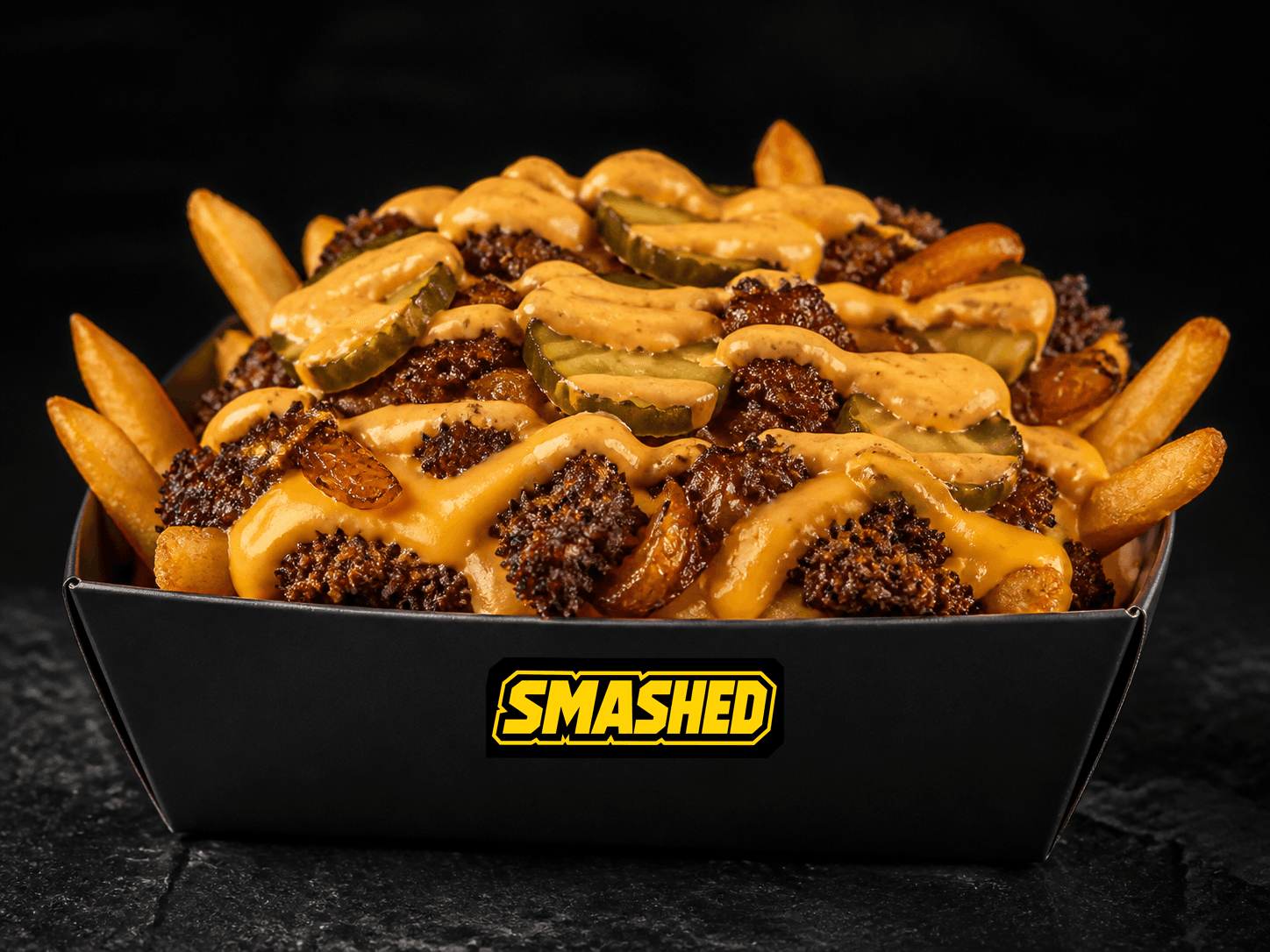 Loaded fries with crispy chopped smash patty, cheese, onions, pickles, and sauce in a black SMASHED box